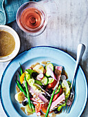 Salad Nicoise with dressing served with a glass of rosé wine