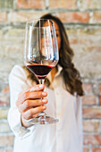 Sommelierin in weißem Hemd mit einem Glas Rotwein in der Hand in einem Restaurant