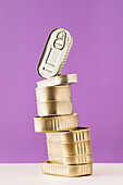 Stacked unopened metal gold color cans on purple background