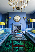 Sofas mit marmoriertem Stoffdesign, Couchtisch mit Marmorplatte und Teppich mit Malachitmuster im Wohnzimmer mit blauen Wänden