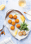 Top view of Arancini rice balls placed on metal tray on table with lemon and cutlery