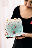 Frau hält dekorative Torte mit Muschelverzierung