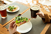 Hände halten Pizzastück und ein Glas dunkles Bier in einem Restaurant