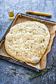 Vegan focaccia with rosemary and sesame seeds unbaked on baking tray