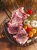 Raw pork chops with vegetables on a barbecue grill