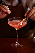 Bartender garnishing a blood orange cocktail