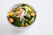 Spinach salad with chicken and croutons in a small bowl