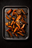 Roasted butternut squash with garlic, sage, sea salt, and black pepper on a baking sheet