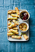 Spring rolls filled with bean puree, capers and chicory with a walnut dip