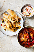 Naan bread rolls with a potato curry filling, carrot raita and spiced tomatoes