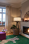 Silk carpet with leopard skin design in front of fireplace, designer floor lamp in room corner