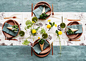 Sommerlich gedeckter Tisch mit braunen Tellern und Löwenzahnblüten