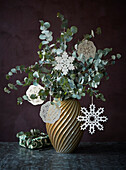 Eucalyptus branches with snowflake baubles in retro vase