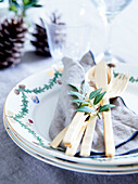 Christmas place setting with gold-coloured cutlery and twig