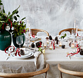 Christmas table setting with bouquets of flowers, pine cones and lanterns