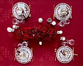 Gedeckter Weihnachtstisch mit roter Tischdecke und Girlande aus rotem Weihnachtsstern