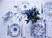 Gedeckter Tisch mit blau-weißem Geschirr und Blumenstrauß in Blautönen