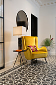 Yellow retro armchair with side table on cement tiles