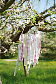 DIY-Deko aus Stoff hängt in einem blühenden Apfelbaum