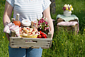 Woman carrying picnic basket with pastries and strawberries