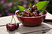 Cherries in a red bowl on a wooden table