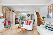 Sitting area with various pieces of furniture, wooden armoire, and dining area in the background