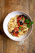 Spaghetti with tomato and olive sauce in bowl and fork