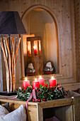 Advent wreath made from natural materials with red candles and table lamp