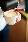 Barista pours milk foam to make latte art