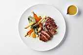 Sliced steak with roast vegetables and sauce