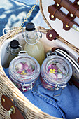 Picnic basket with preserving jars and drinks in glass bottles