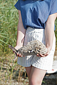 Person holding a decorative fish made from driftwood