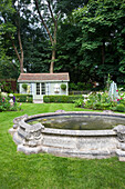 Antiker Teich in gepflegtem Garten, im Hintergrund Sommerhaus