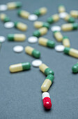 Red and white pills among green and yellow pills