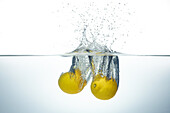 Two lemons splashing in water