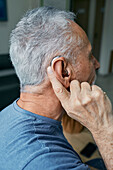 Man adjusting hearing aid