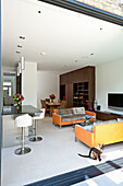 Upholstered sofas in front of a breakfast bar in open-plan living room with a dining area in the background