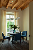 Blue leather chairs around a round table in a room with a woodbeamed ceiling