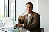 A young businessman sitting in an office wearing a brown blazer