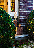 Decorative wooden sculptures in candle look at a Christmas-lit entrance to the house