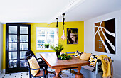 Holztisch mit Stühlen und Sitzbank und Kunstwerke an den Wänden in einer Küche