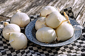 White onions on a blue tin plate on a wooden table