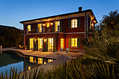 An illuminated two-storey villa with a pool