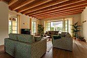 Polstersofas und Fernseher in einer Lounge mit Holzdecke und Terrassenzugang