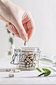 A hand taking a supplements from an open jar
