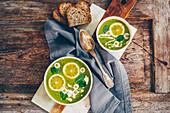Potato and broccoli soup with wild garlic, lemon slices and daisies