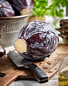 Red cabbage with a knife on a wooden cutting board