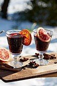 Mulled wine with blood orange on a table in a wintery garden