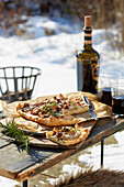 Pear and cheese tart with cranberries and nuts on a table in a wintery garden
