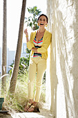 Young brunette woman wearing a striped tankini top, yellow pants and jacket